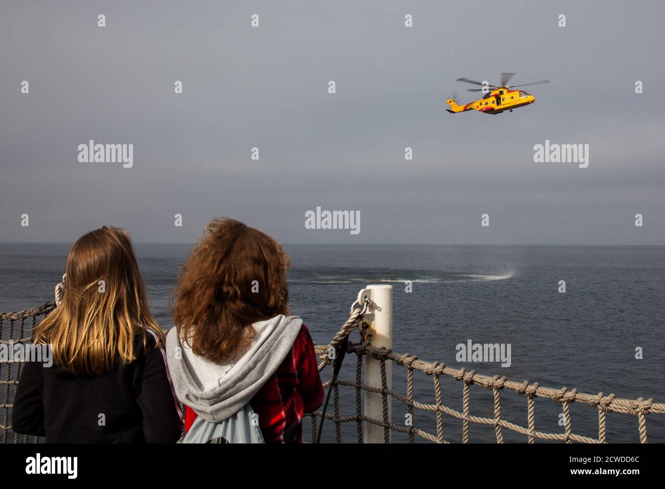 À bord d'un navire de guerre de la base des Forces canadiennes à Esquimalt, en Colombie-Britannique, une paire de femmes regardent une démonstration de recherche et de sauvetage d'un CH- Banque D'Images