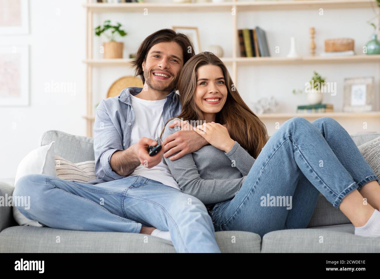 Un jeune couple joyeux regardant la télévision ensemble à la maison Banque D'Images