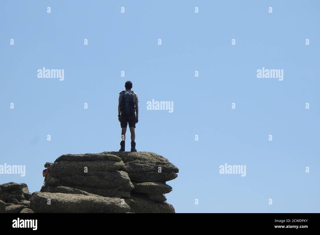 Randonneur aventureux se tenant au sommet de la falaise et regardant au ciel Banque D'Images