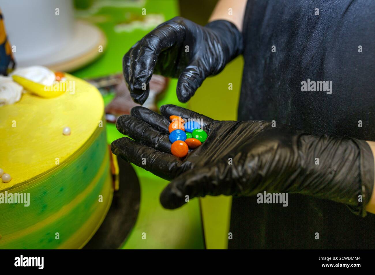 chef pâtissier décorant le gâteau dans la cuisine. Décorations colorées Banque D'Images