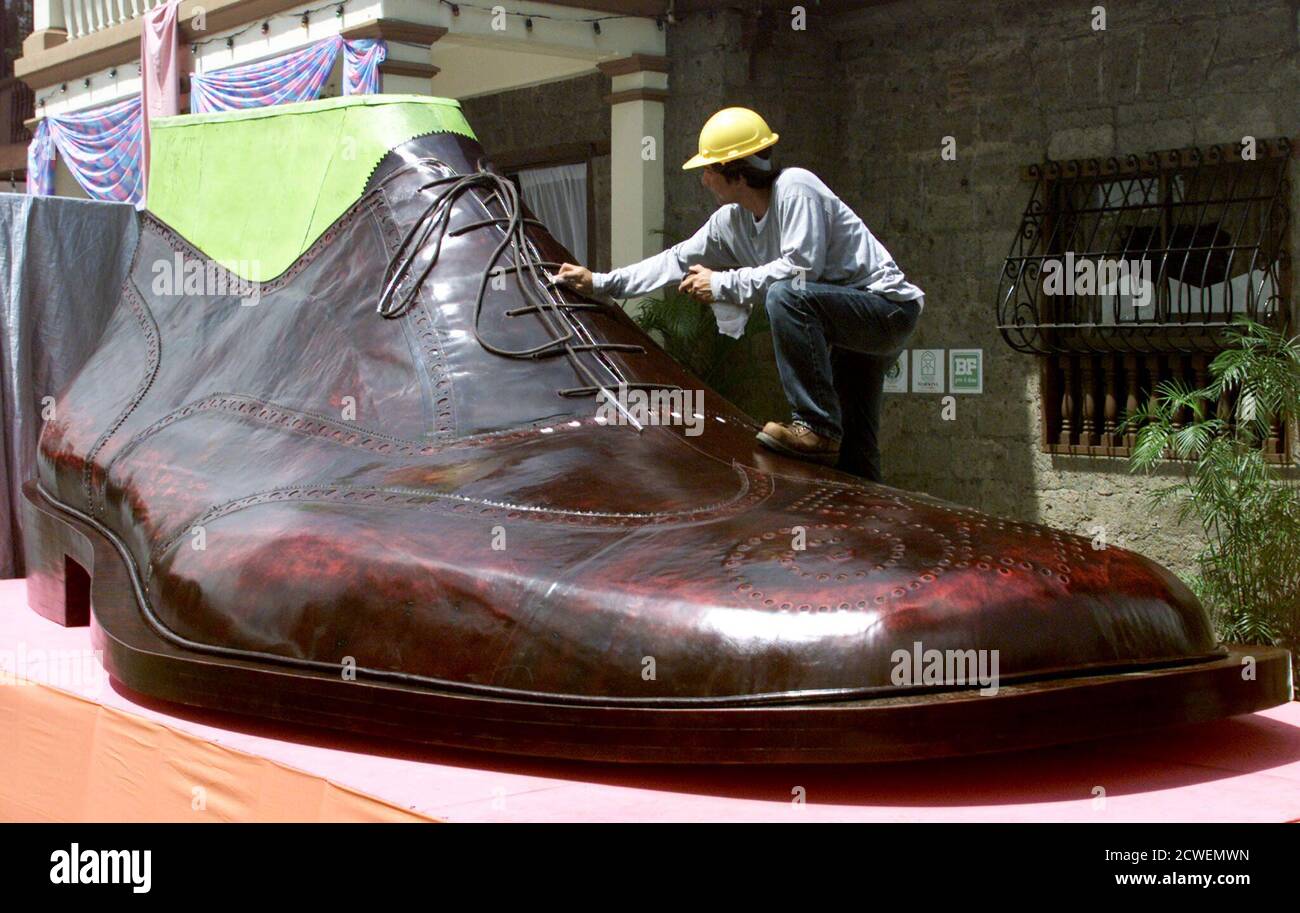 Un travailleur philippin nettoie une chaussure géante, qui serait la plus  grande au monde, en vue de son dévoilement dans la ville de Marikina, à  l'est de Manille, le 21 octobre 2002.