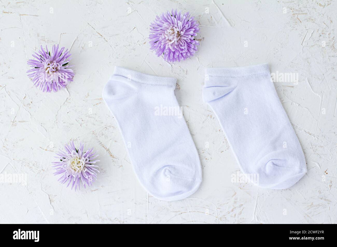 Paire de chaussettes pour femmes et fleurs de chrysanthème sur fond blanc structuré, vue du dessus. Banque D'Images