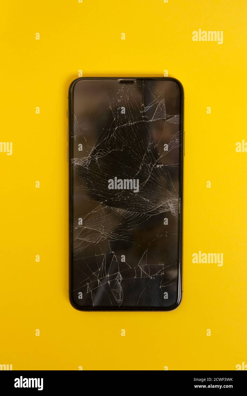 Écran de smartphone cassé sur fond jaune. Gros plan sur un téléphone fissuré. Banque D'Images