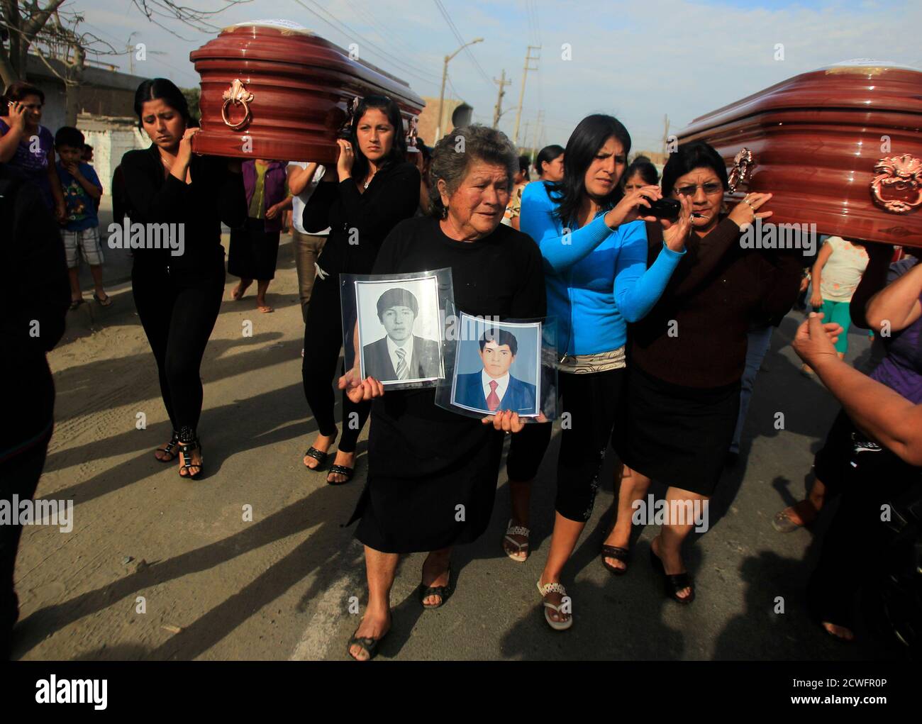 Laura Saenz, mother in law of the victim Carlos Tarazona holds photos of  Carlos and his brother Jorge Luis as their coffins are carried for a mass  at the main square in