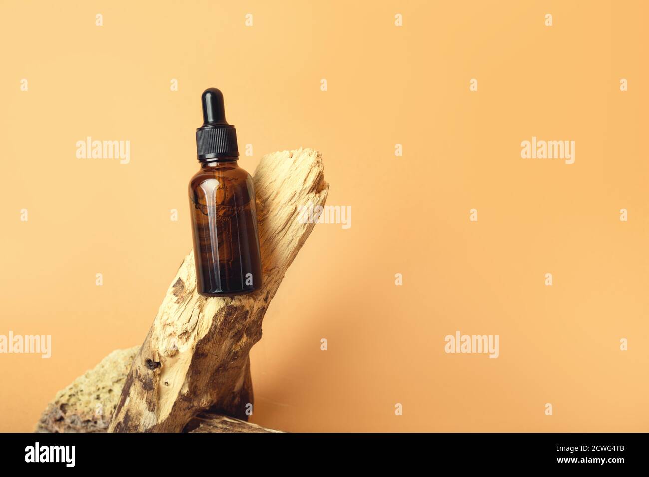 Un flacon compte-gouttes en verre sur fond orange. Banque D'Images