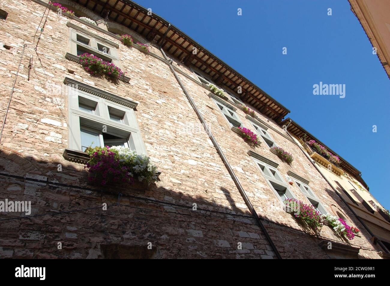 vue en angle sur une maison médiévale et fleurs sur les fenêtres Dans le village de Spello en Ombrie et clair été ciel au-dessus Banque D'Images