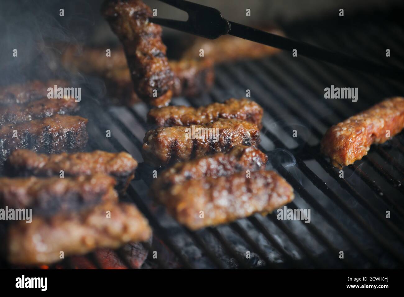Image de faible profondeur de champ (mise au point sélective) avec mici traditionnel roumain (mititei), rouleaux de viande hachée grillés en forme cylindrique sur le barbecue Banque D'Images