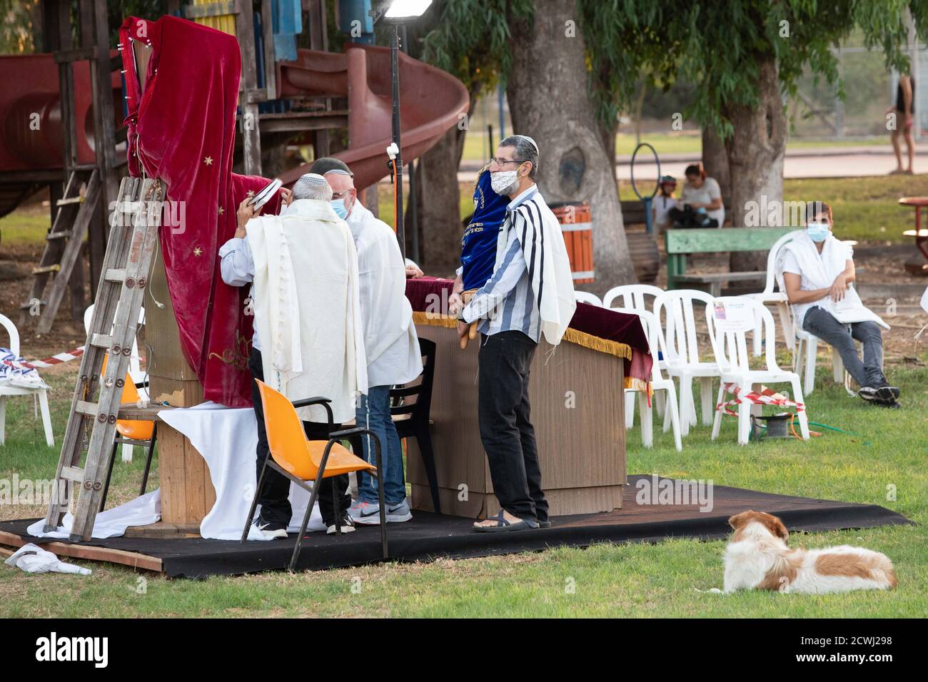 En raison de la COVID-19, prières sur le jour juif des Expiations, (Yom Kippur). Ont été maintenus en plein air tout en essayant de maintenir la distance personnelle amd porter des masques chirurgicaux. Tandis que les Israéliens laïques peuvent être vus à vélo et jouer dans le parc. L'épidémie de COVID-19 a forcé les gouvernements du monde entier à imposer une quarantaine civile. Le résultat est un contact limité entre les gens et une interaction sociale minimale. Photographié à Kfar Yona Israel le 28 2020 septembre Banque D'Images