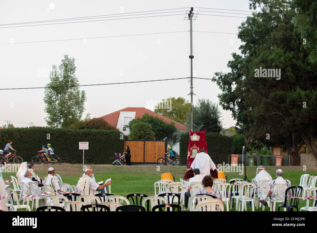 En raison de la COVID-19, prières sur le jour juif des Expiations, (Yom Kippur). Ont été maintenus en plein air tout en essayant de maintenir la distance personnelle amd porter des masques chirurgicaux. Tandis que les Israéliens laïques peuvent être vus à vélo et jouer dans le parc. L'épidémie de COVID-19 a forcé les gouvernements du monde entier à imposer une quarantaine civile. Le résultat est un contact limité entre les gens et une interaction sociale minimale. Photographié à Kfar Yona Israel le 28 2020 septembre Banque D'Images