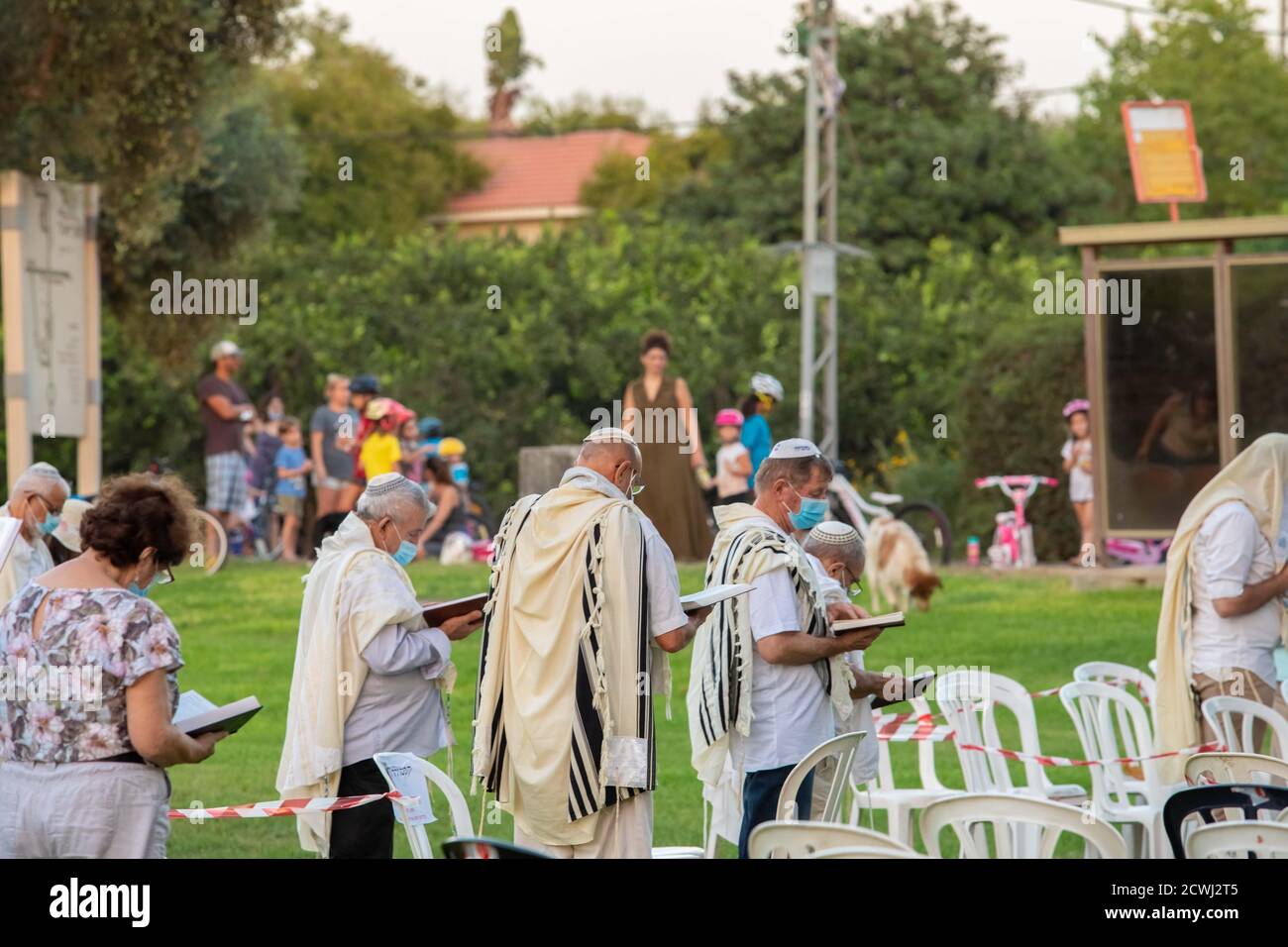 En raison de la COVID-19, prières sur le jour juif des Expiations, (Yom Kippur). Ont été maintenus en plein air tout en essayant de maintenir la distance personnelle amd porter des masques chirurgicaux. Tandis que les Israéliens laïques peuvent être vus à vélo et jouer dans le parc. L'épidémie de COVID-19 a forcé les gouvernements du monde entier à imposer une quarantaine civile. Le résultat est un contact limité entre les gens et une interaction sociale minimale. Photographié à Kfar Yona Israel le 28 2020 septembre Banque D'Images