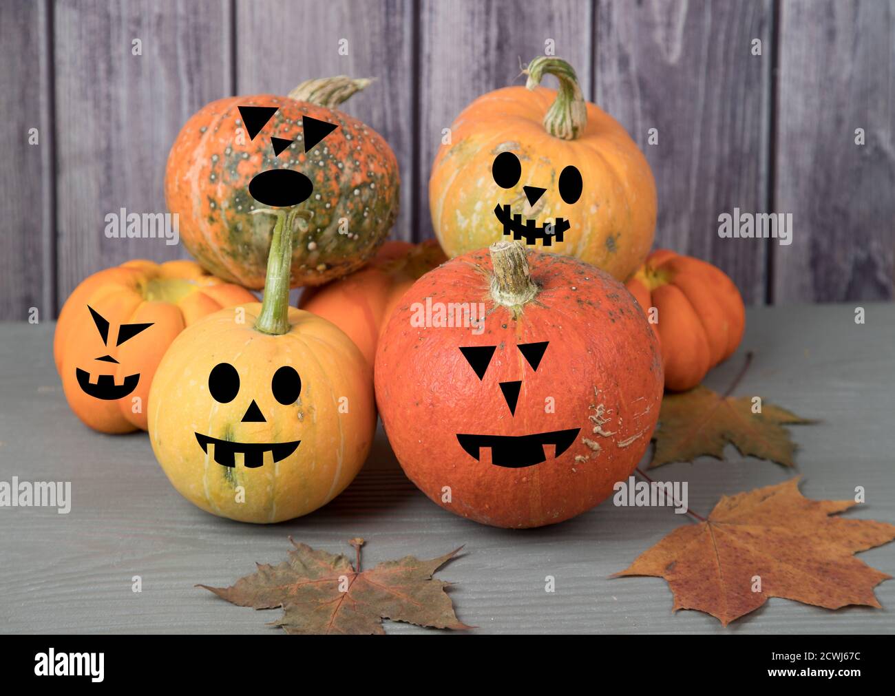 Pyramide de la récolte de citrouille avec des masques impressionnants avec des feuilles d'automne sur un fond en bois gris avant les vacances d'Halloween. Banque D'Images