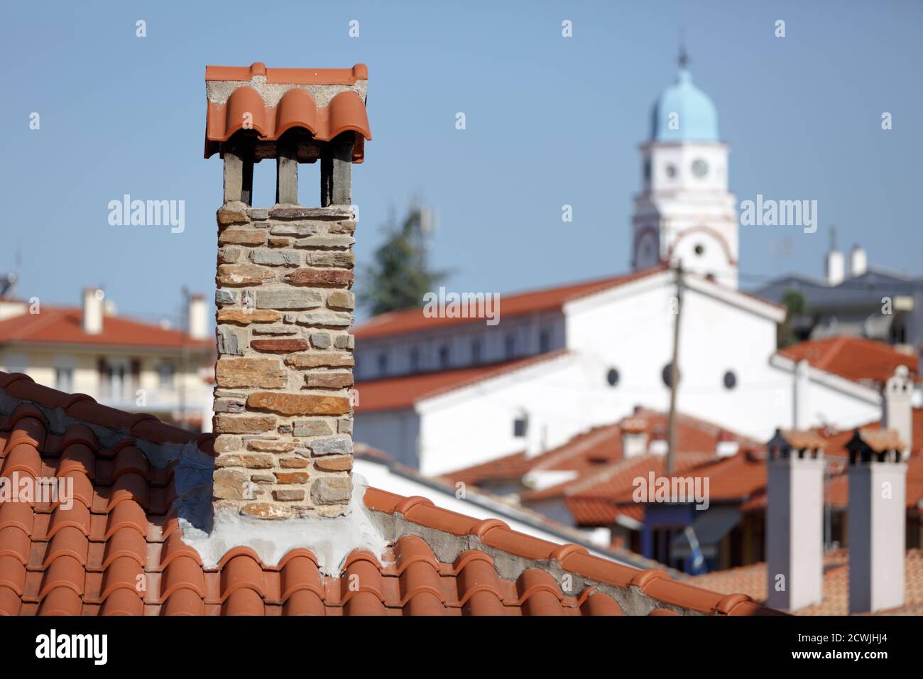toits carrelés rouges avec cheminées en pierre sur le fond de Une église blanche avec un dôme bleu sur l'île De Thassos en Grèce Banque D'Images