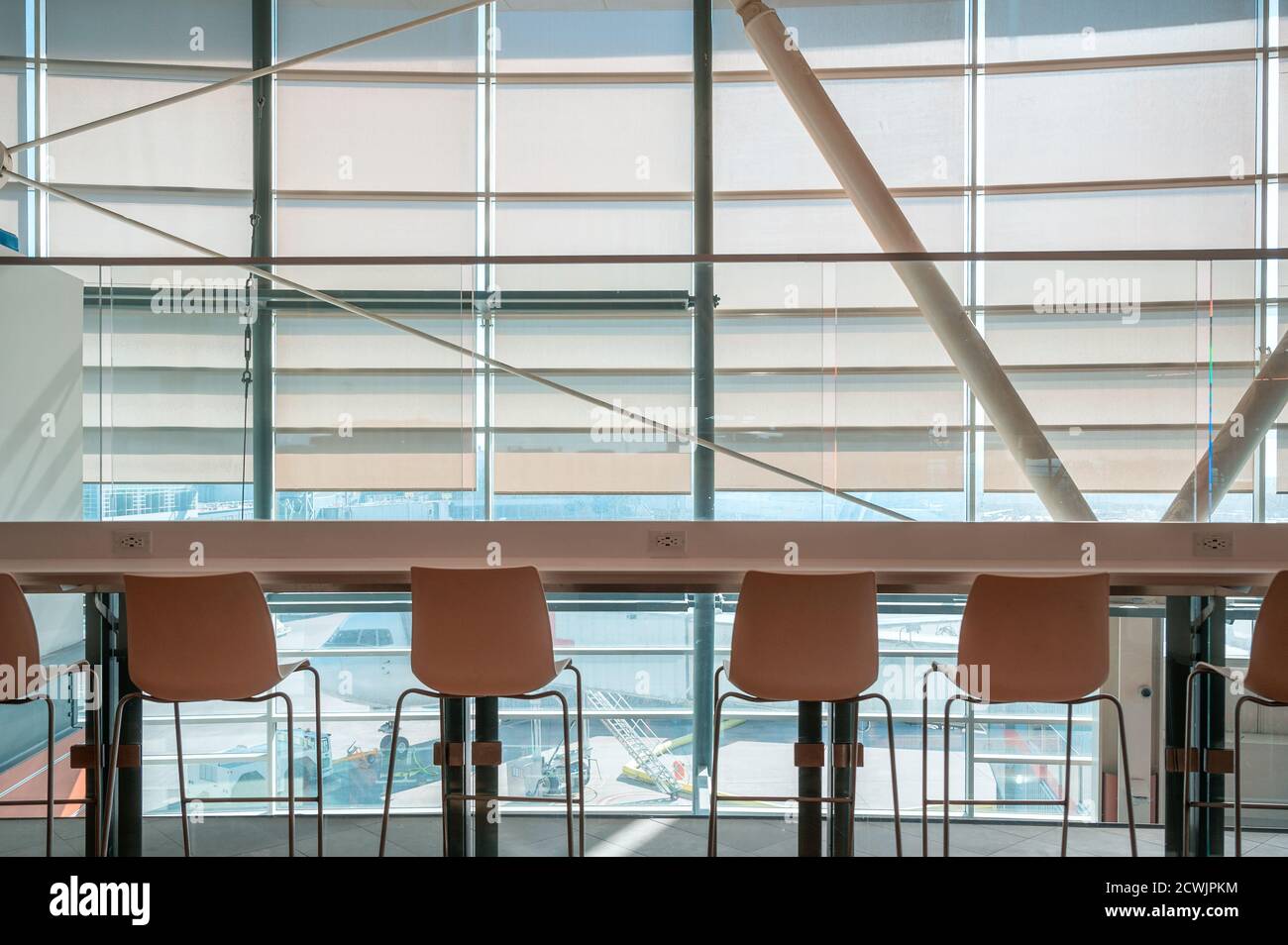 Rangée de chaises avec table de comptoir en bois sur vitre avec l'aéroport dans le salon Banque D'Images