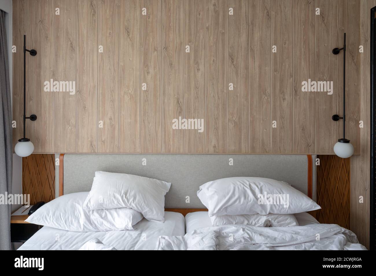 Tête de lit en bois avec lampe de la chambre avec oreiller froissé et couverture Banque D'Images