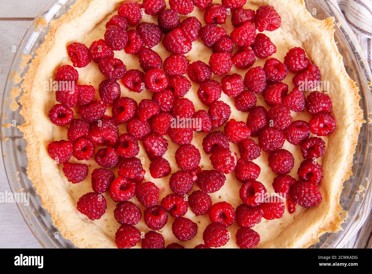 Préparation d'une tarte sablée aux framboises sur fond de bois blanc, vue de dessus de près. Banque D'Images