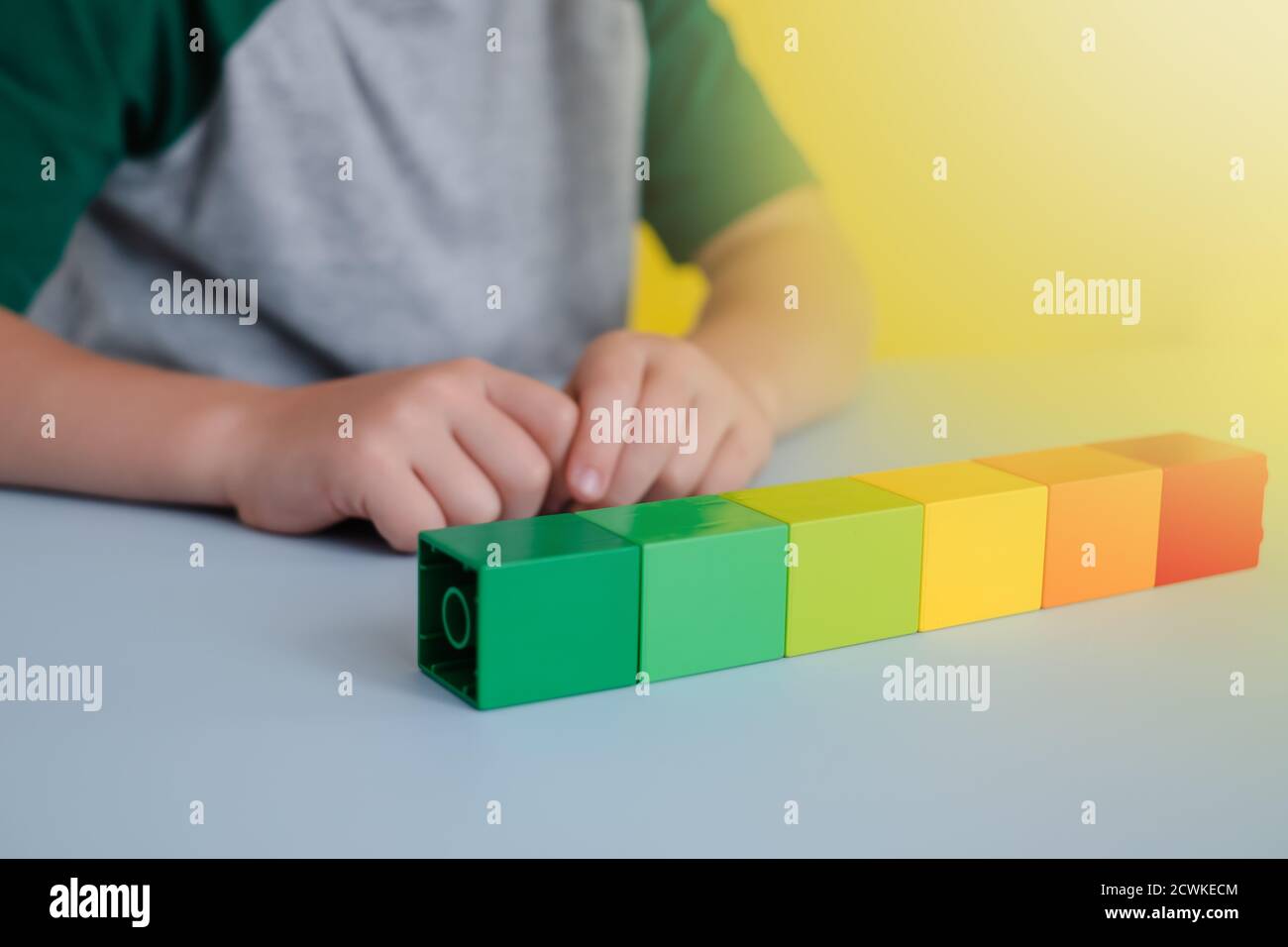 blocs colorés dans une ligne sur la table. sur le fond des mains des enfants.concept de développement précoce Banque D'Images