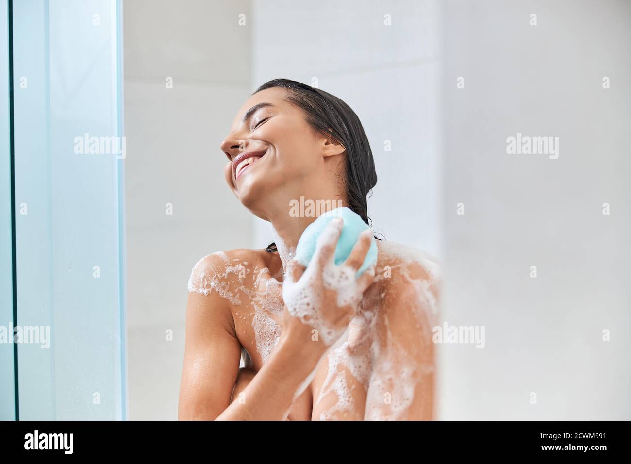 Joyeuse jeune femme utilisant bain loofah tout en prenant la douche Photo  Stock - Alamy