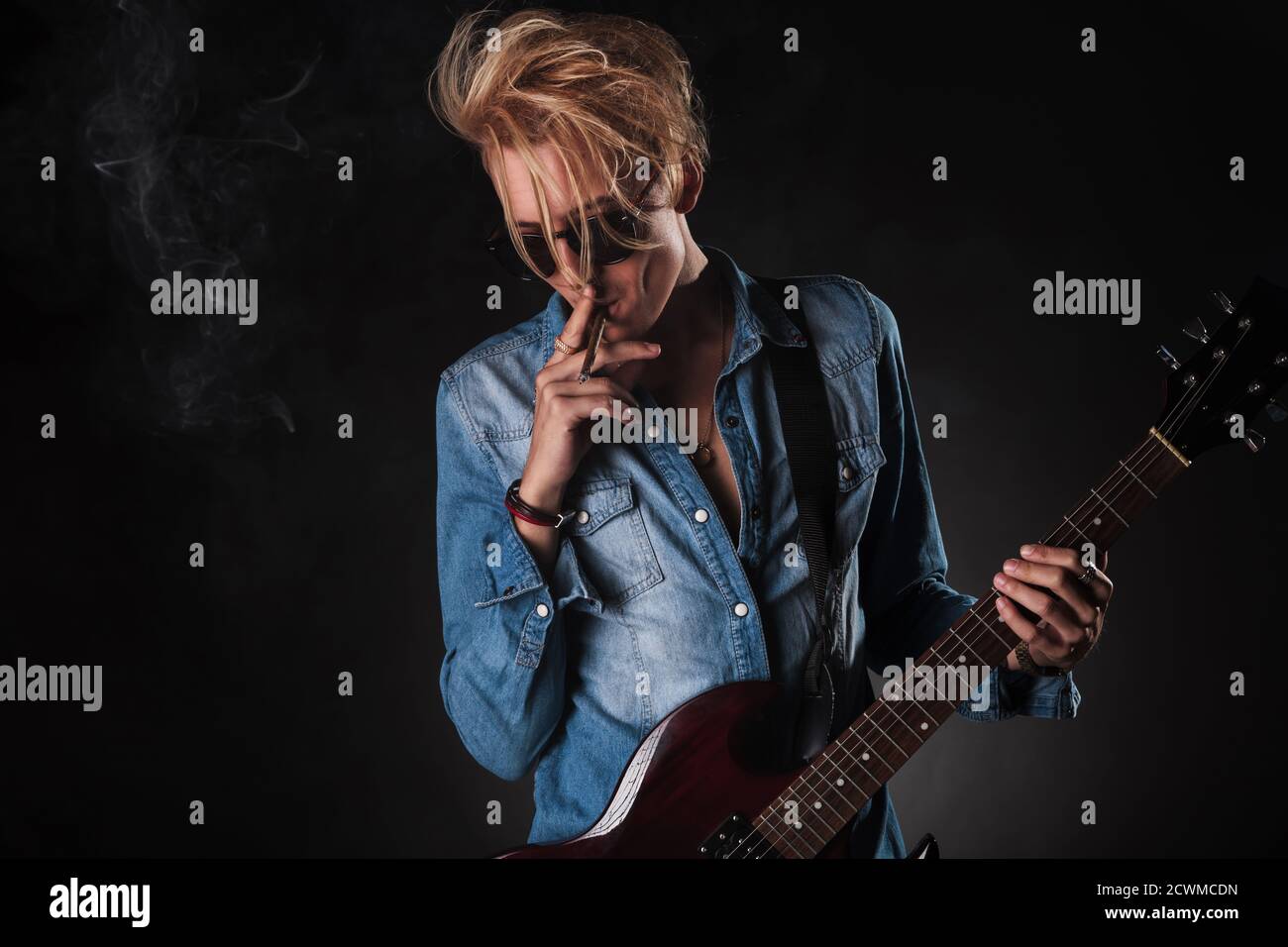 génial jeune guitariste fumant et jouant de la guitare électrique en studio Banque D'Images