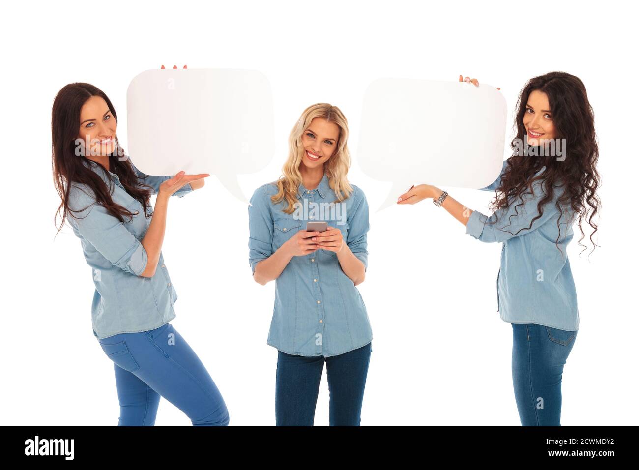 jeune femme blonde envoyant des sms sur son téléphone et ses amis tenez des bulles de parole près d'elle sur fond blanc de studio Banque D'Images