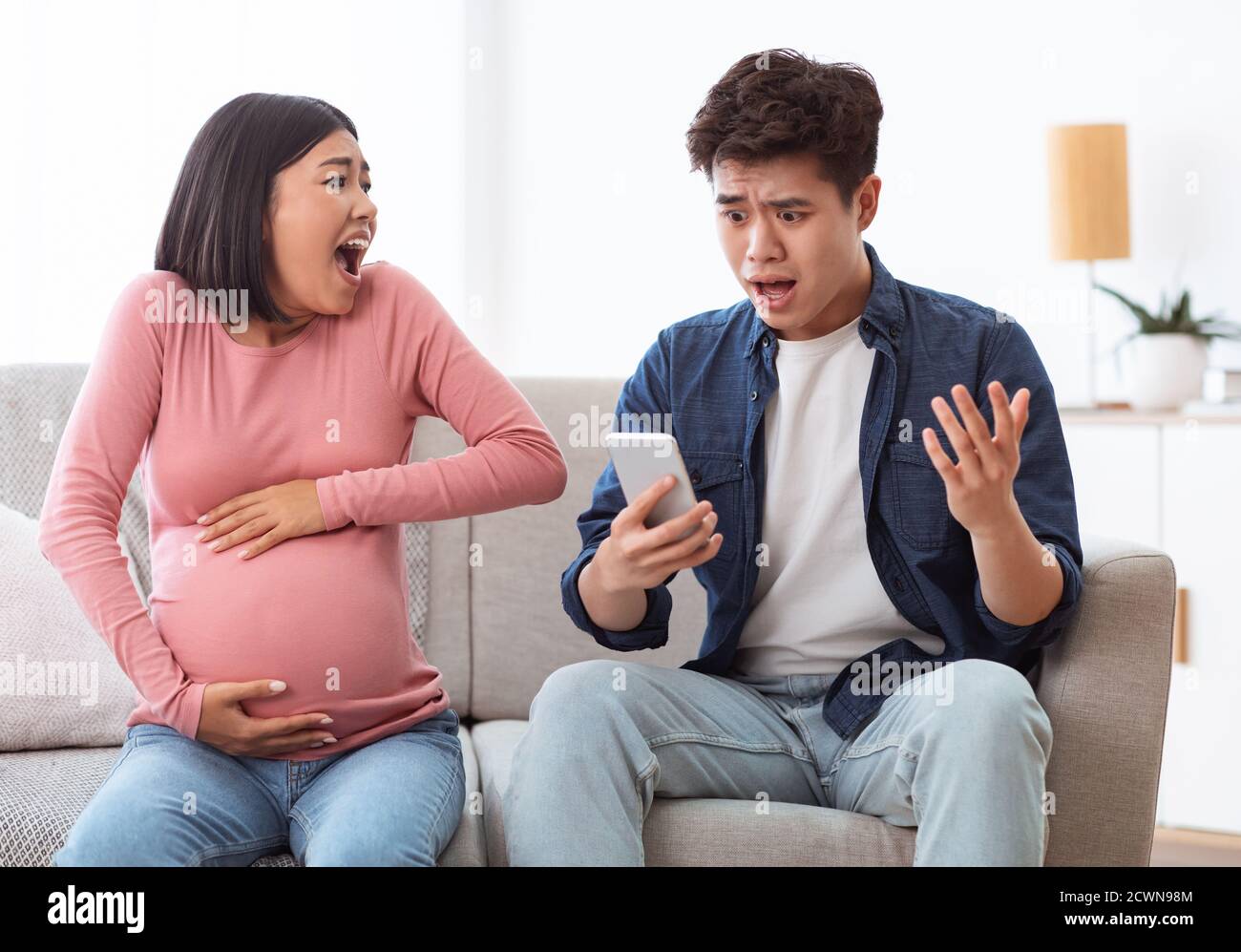 Un mari asiatique choqué appelle l'urgence pour une femme enceinte à la maison Banque D'Images