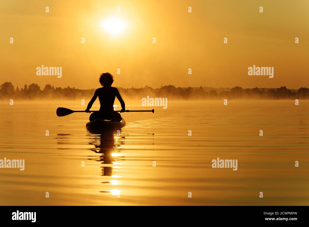 Jeune homme sportif assis sur un plan supérieur avec une longue paddle Banque D'Images