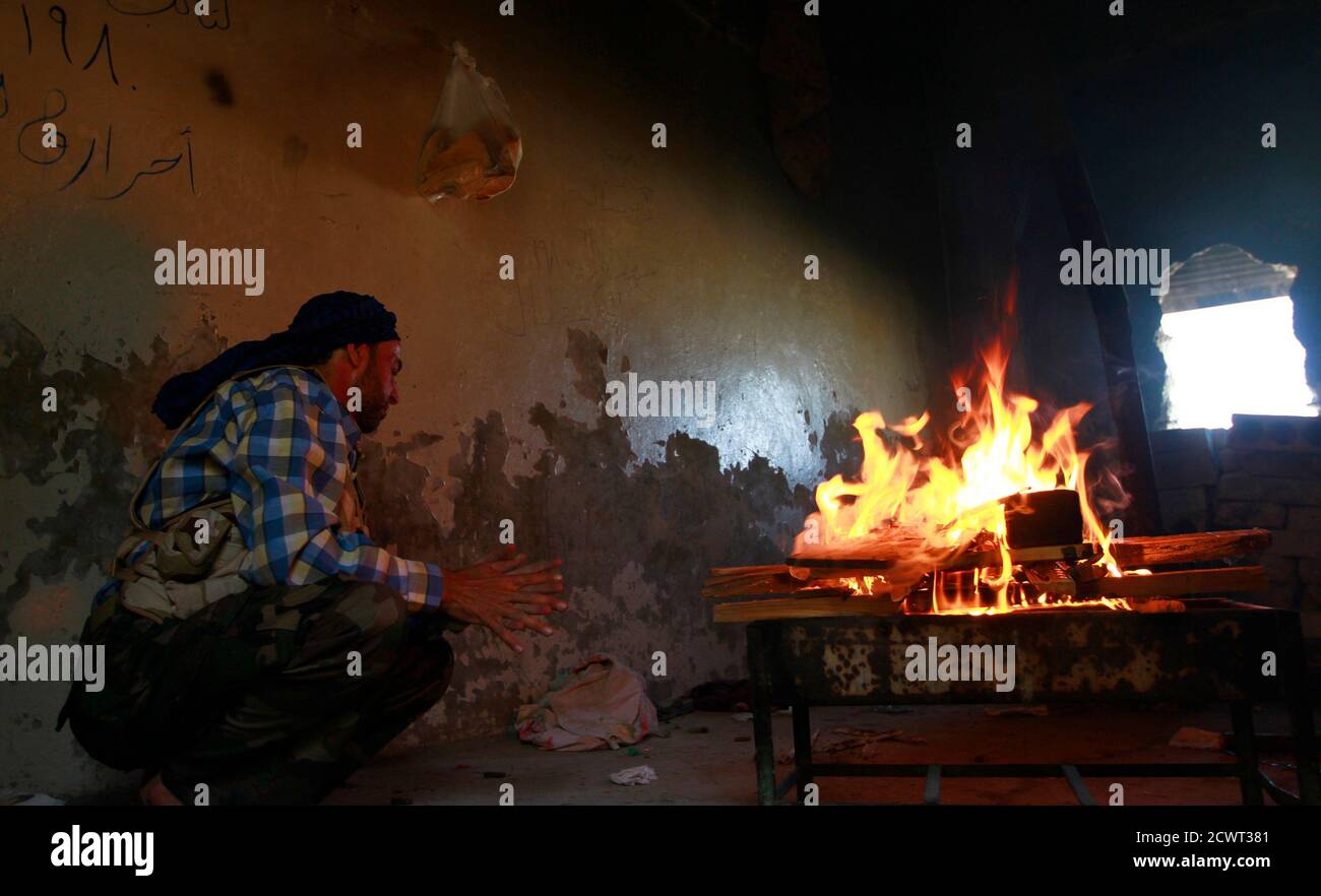 A member of the Free Syrian Army sits near a fire to prepare food near Nairab military airport, in Aleppo June 27, 2013. REUTERS/Hamid Khatib (SYRIA - Tags: CONFLICT) Banque D'Images