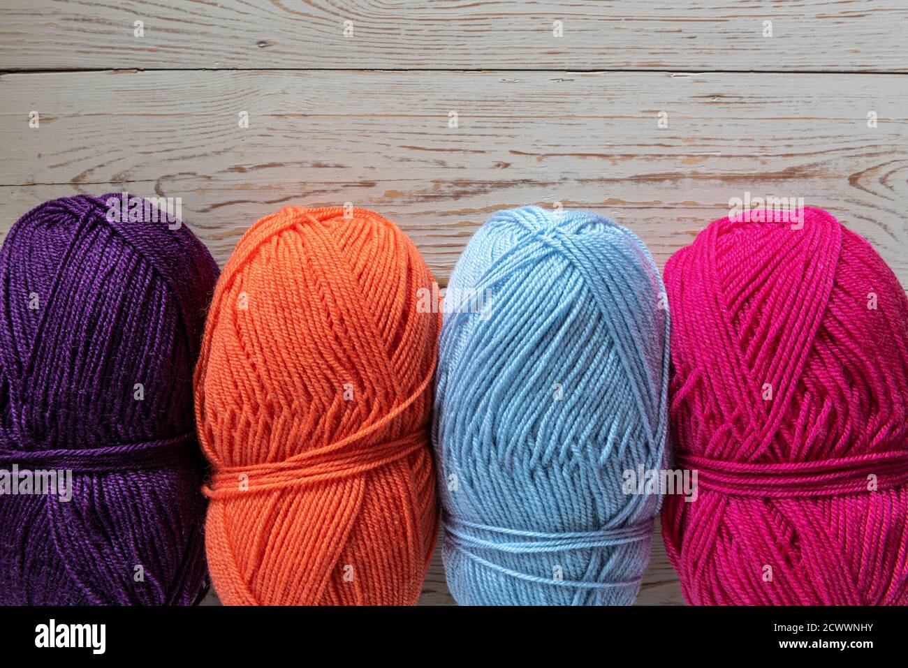 Quatre boules de laine à tricoter de couleur vive. Banque D'Images