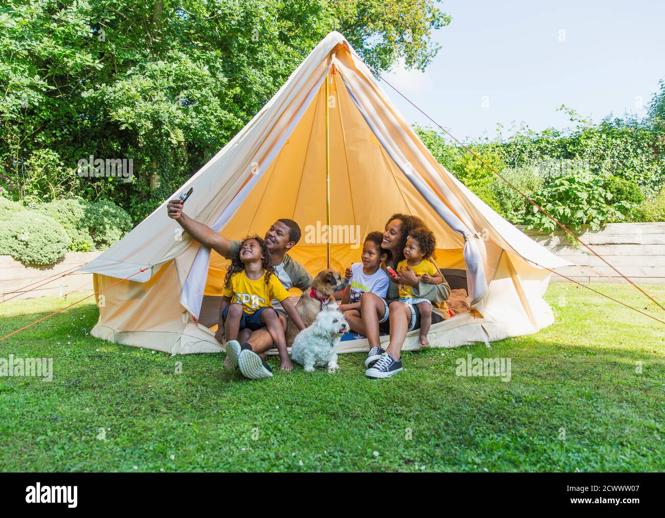 Famille heureuse prenant le selfie dans la tente dans l'arrière-cour d'été Banque D'Images