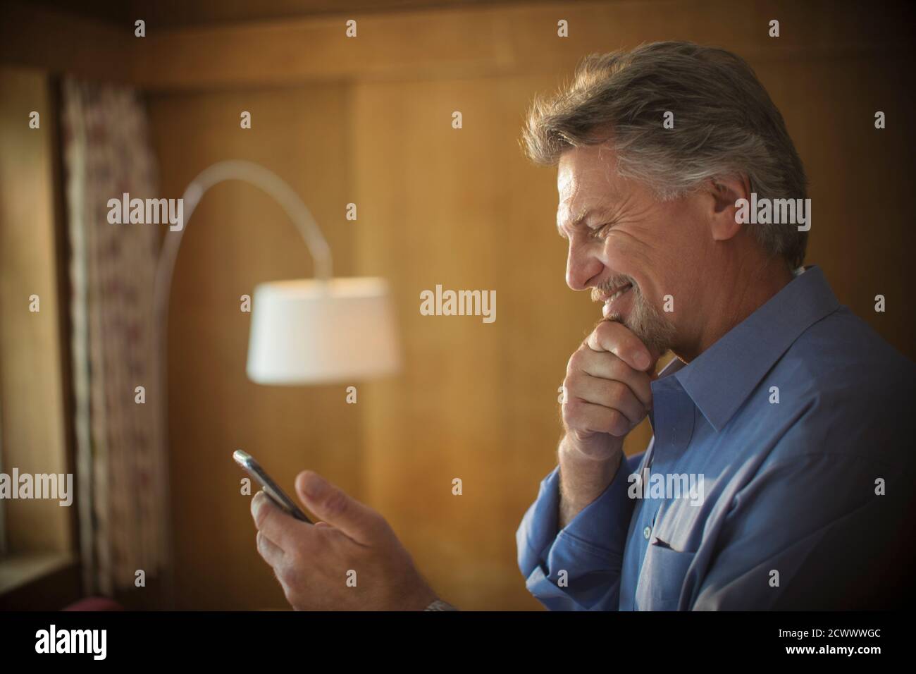 Homme senior souriant utilisant un smartphone à la maison Banque D'Images