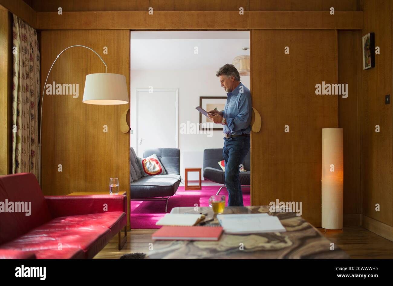 Homme âgé utilisant une tablette numérique dans la porte du salon Banque D'Images