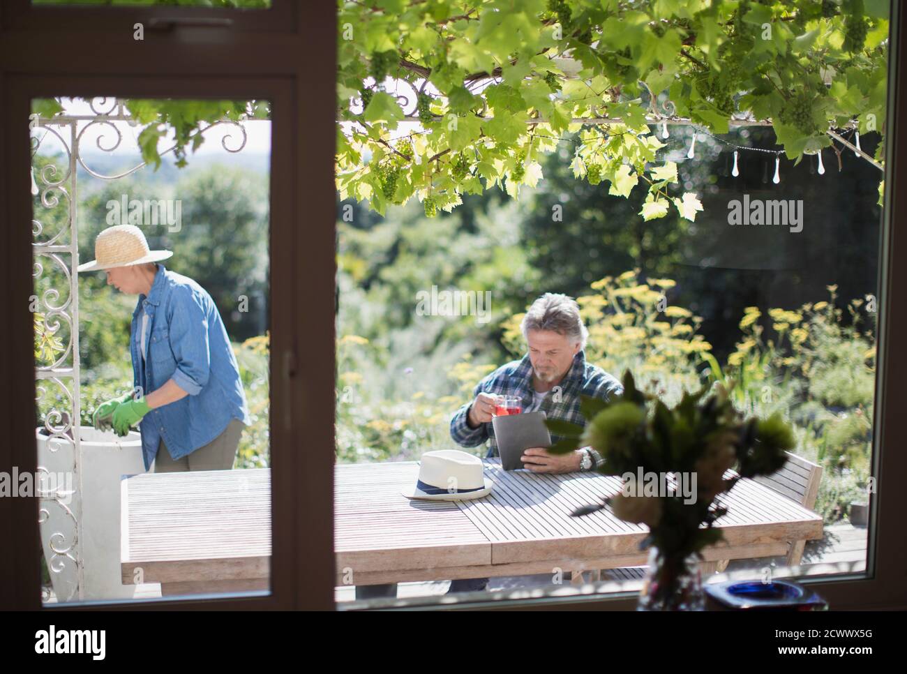 Couple senior jardinant et utilisant la tablette numérique pendant l'été ensoleillé patio Banque D'Images