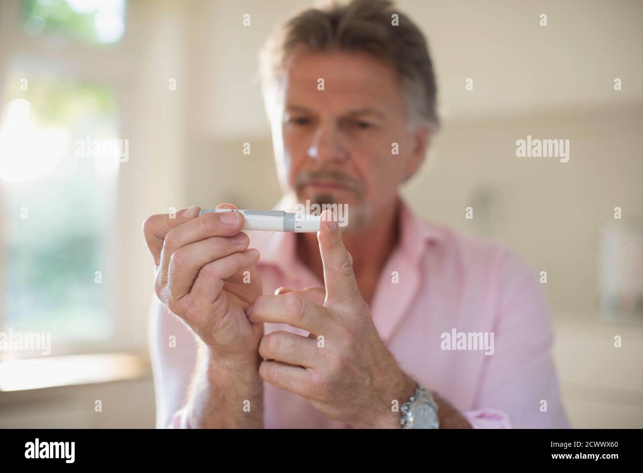 Homme âgé souffrant de diabète utilisant un glucomètre sur le doigt Banque D'Images