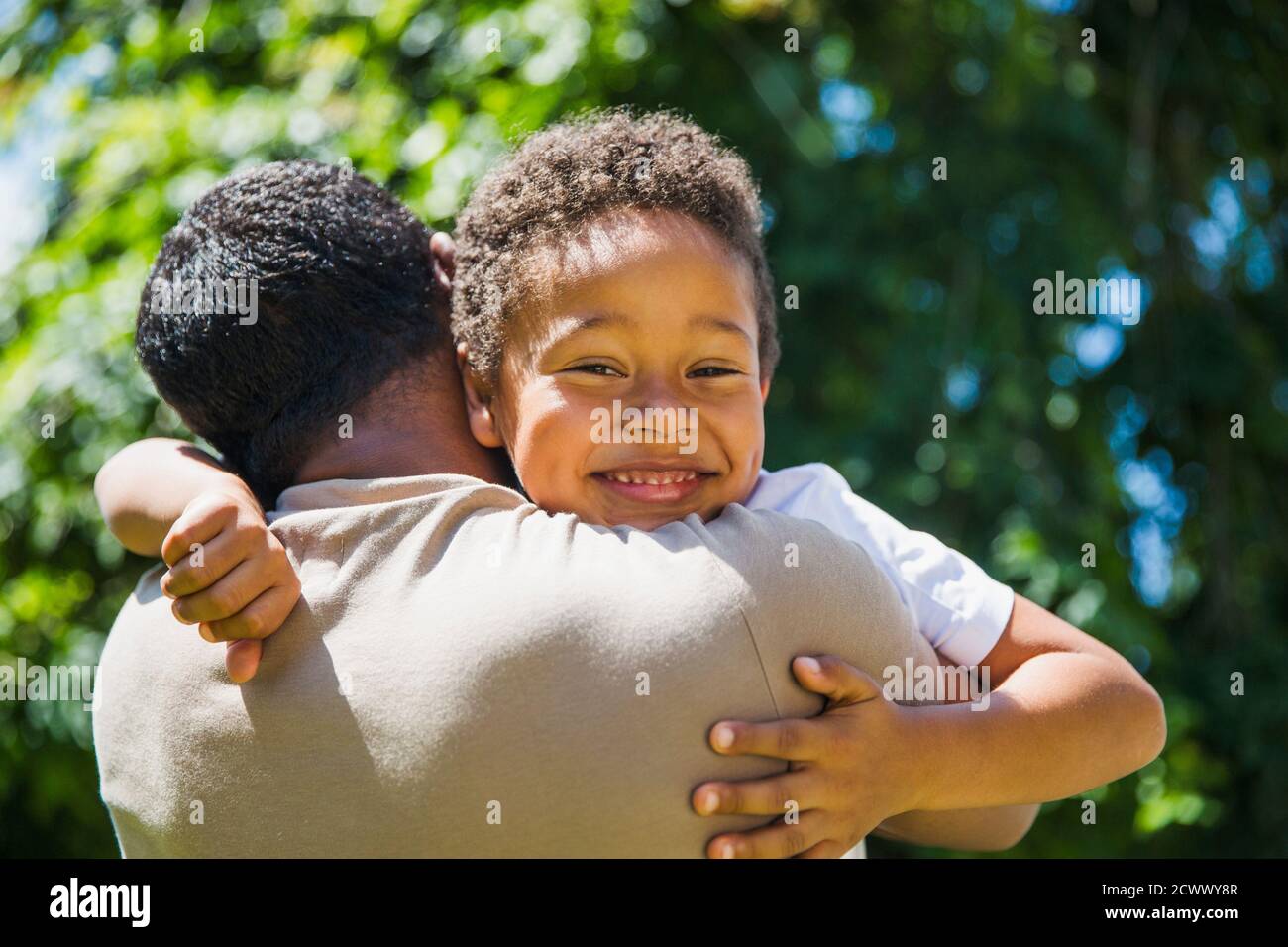 Portrait heureux fils embrassant le père sous le soleil Banque D'Images