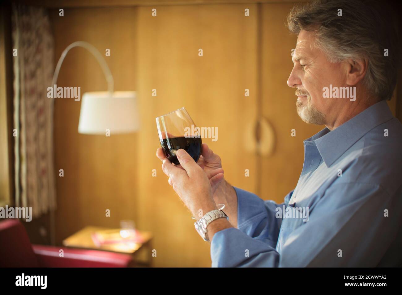 Un homme expérimenté goûtant du vin rouge dans le salon Banque D'Images