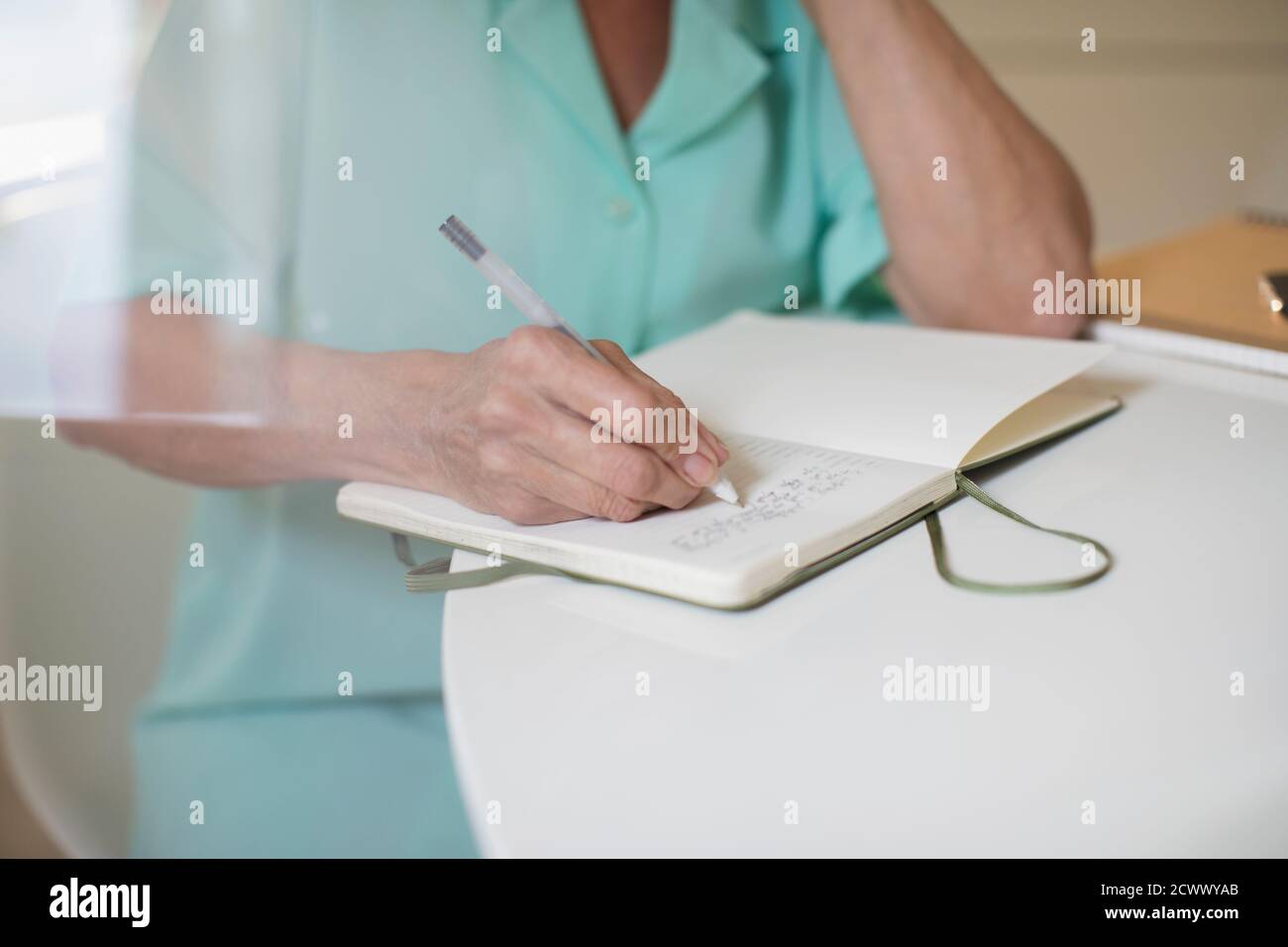 Gros plan femme senior écrivant dans le journal à la table Banque D'Images