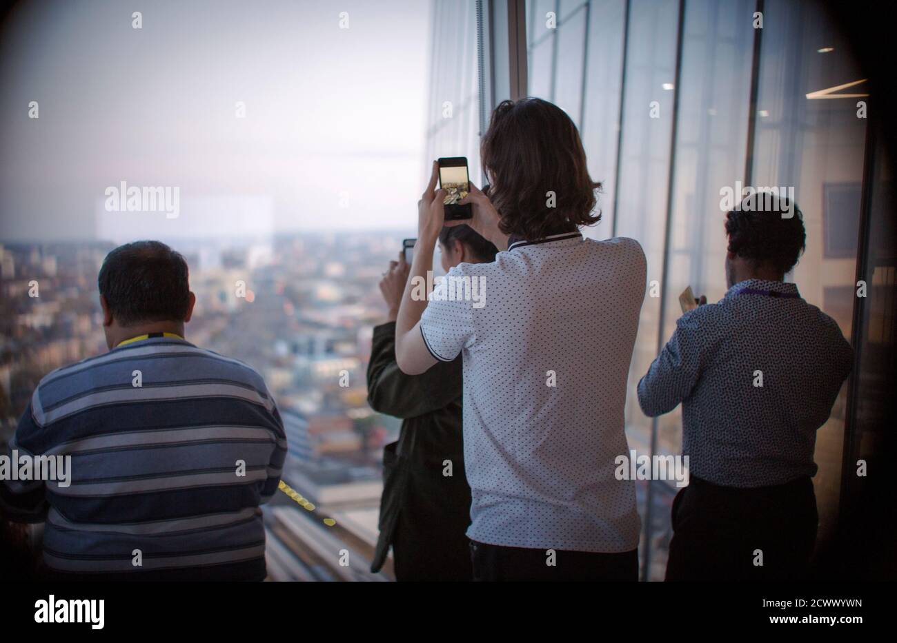 Les gens d'affaires qui utilisent des téléphones avec appareil photo à la fenêtre du bureau urbain Banque D'Images