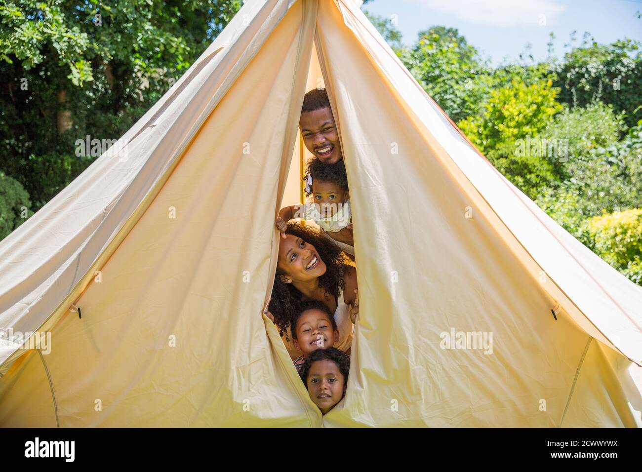 Portrait de famille ludique en train de peer de l'intérieur de la tente Banque D'Images