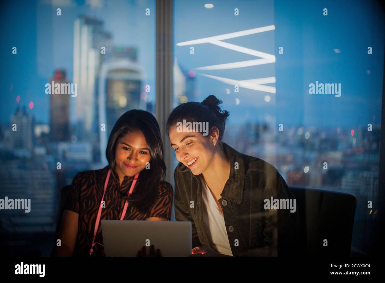 Femmes d'affaires avec tablette numérique travaillant tard dans le bureau, Londres, Royaume-Uni Banque D'Images