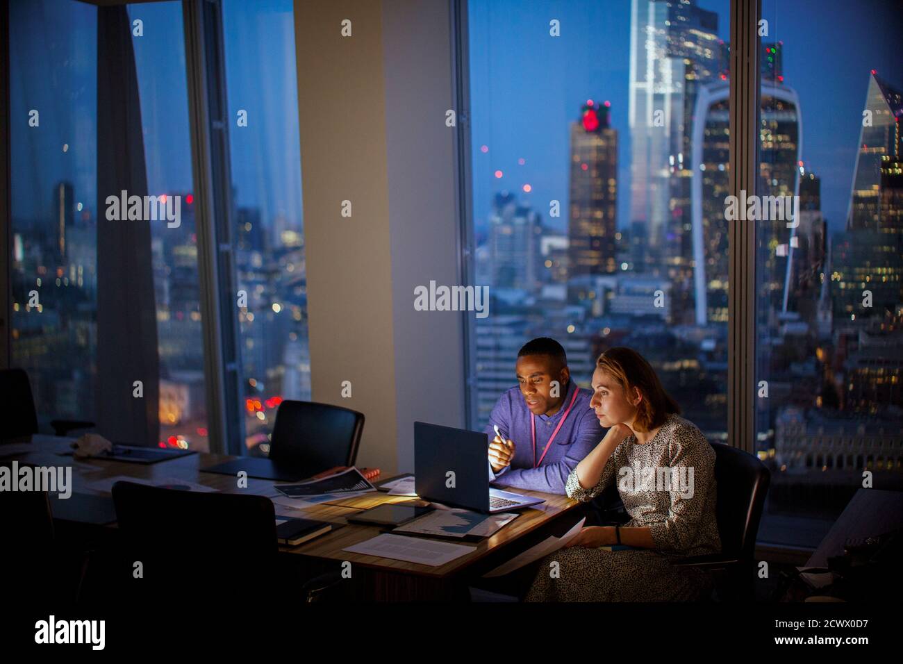 Les professionnels travaillent tard sur un ordinateur portable dans un bureau de grande hauteur, à Londres, au Royaume-Uni Banque D'Images
