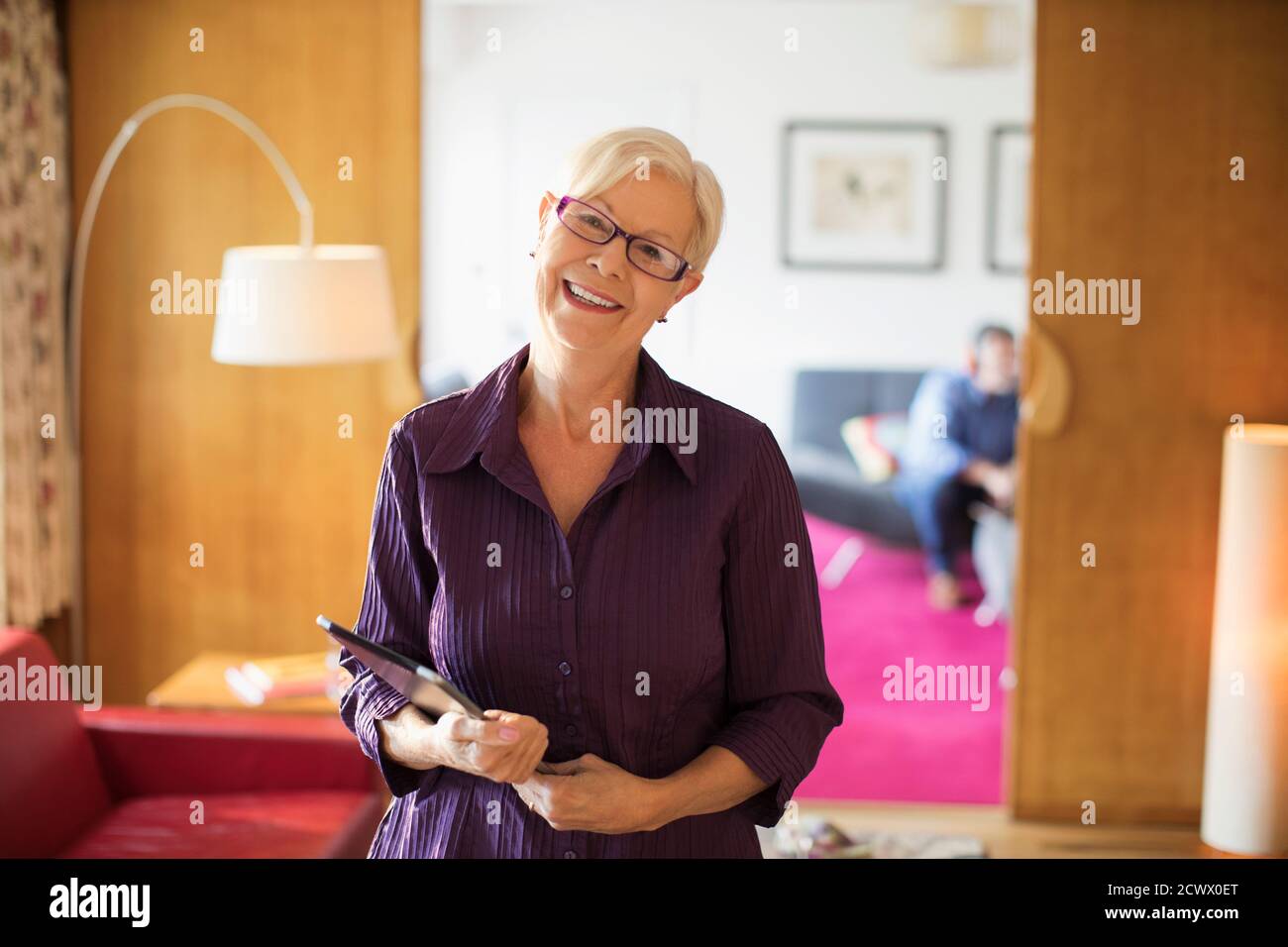 Portrait bonne confiante femme âgée avec une tablette numérique dans la vie chambre Banque D'Images