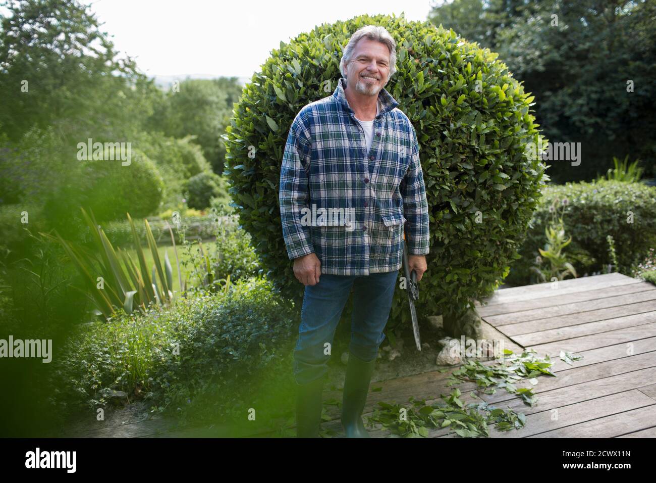 Portrait bon homme âgé jardinant sur le patio Banque D'Images