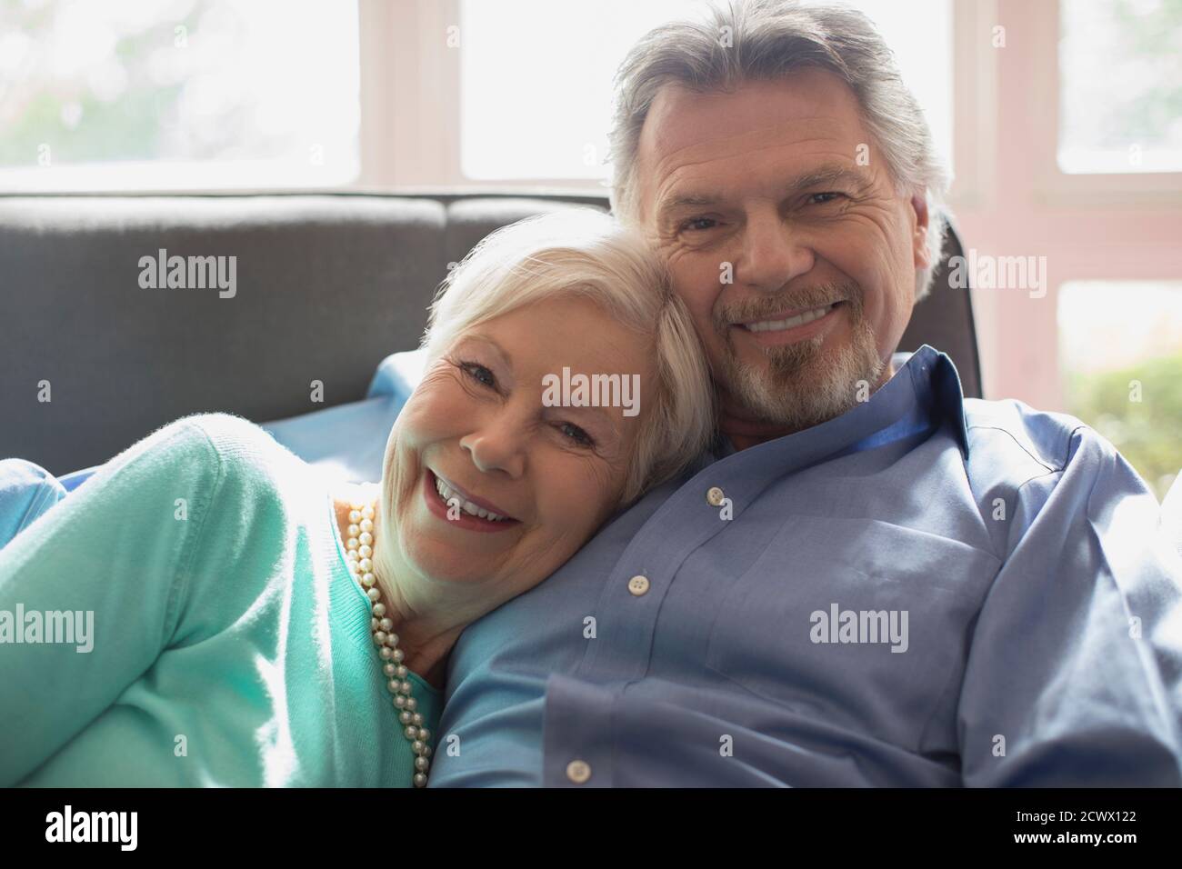 Portrait heureux couple senior en cuddling sur le canapé du salon Banque D'Images