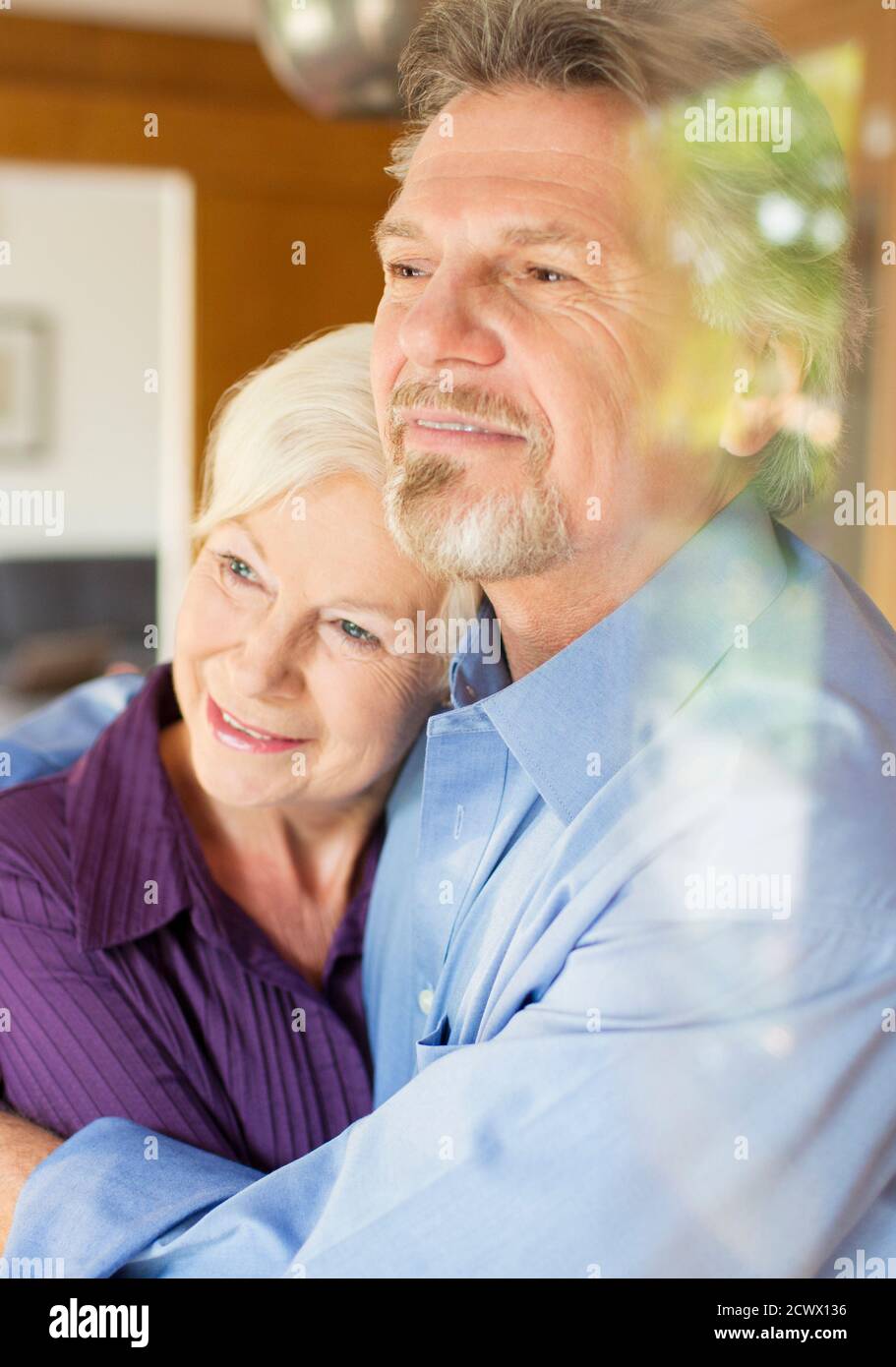 Couple sénior serein qui se serre à la fenêtre Banque D'Images