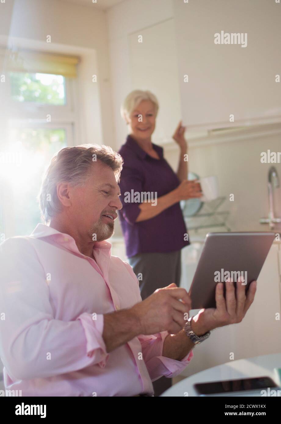 Couple senior avec tablette numérique parlant dans la cuisine Banque D'Images
