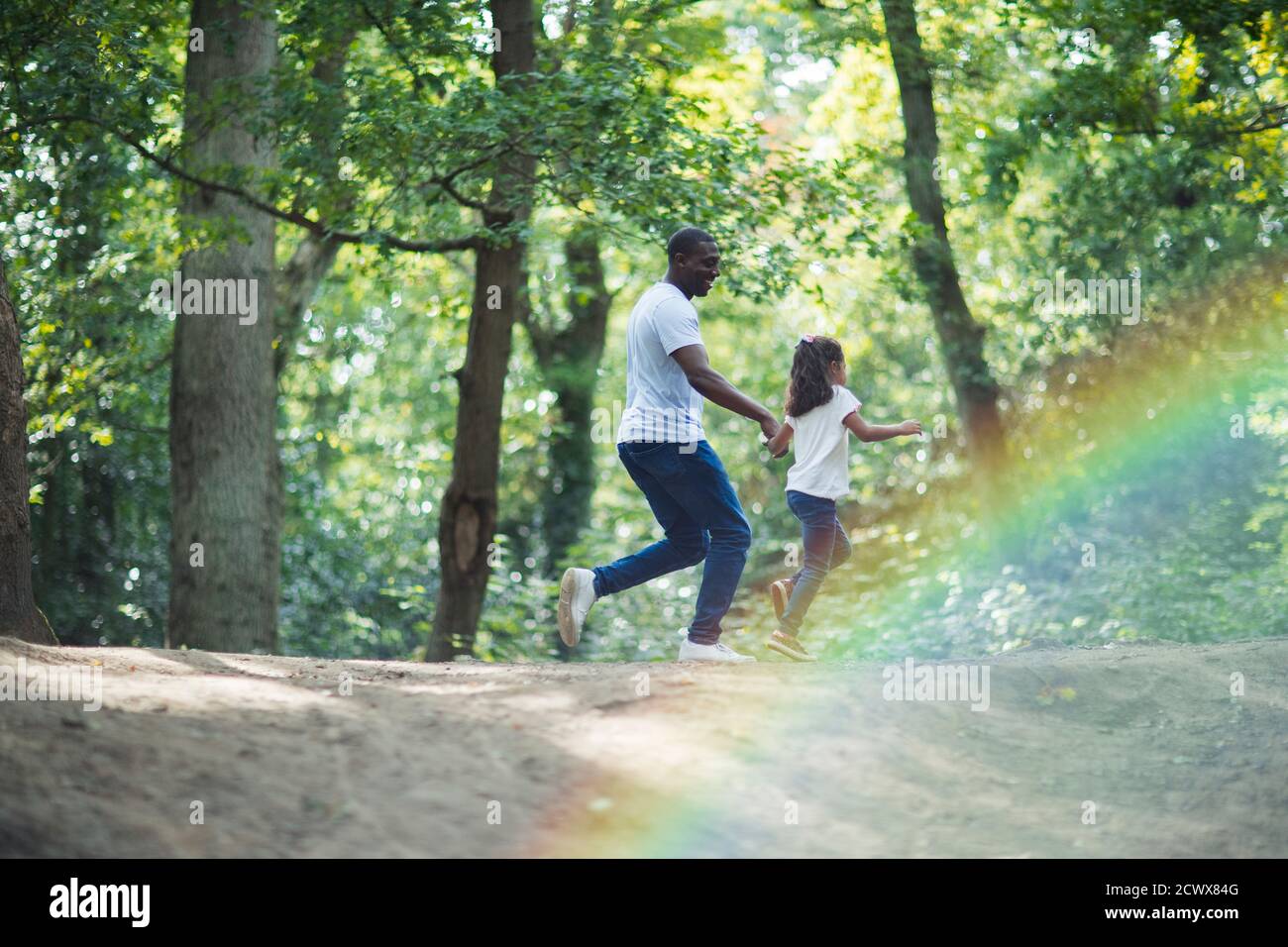 Père et fille heureux courant sur la piste dans les bois d'été Banque D'Images