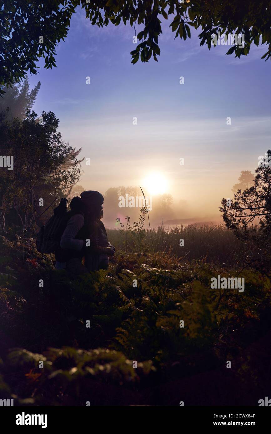 Silhouette affectueuse jeune couple profitant du coucher de soleil pittoresque dans la nature Banque D'Images