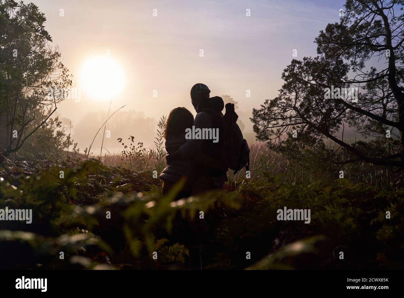Silhouette sereine jeune couple profitant du coucher de soleil dans la nature Banque D'Images