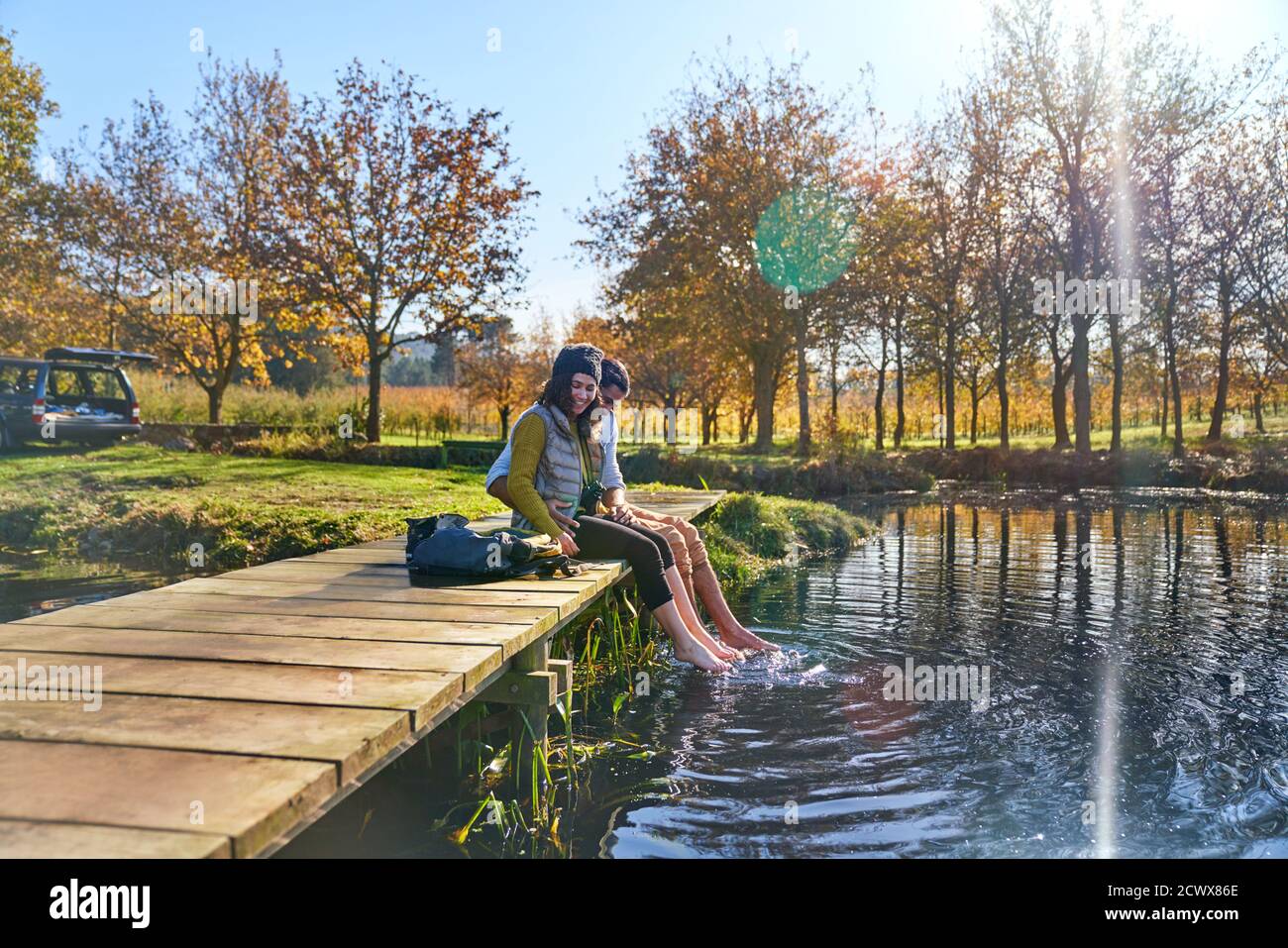Un jeune couple heureux sur le quai plongeant les pieds nus dans le soleil lac d'automne Banque D'Images