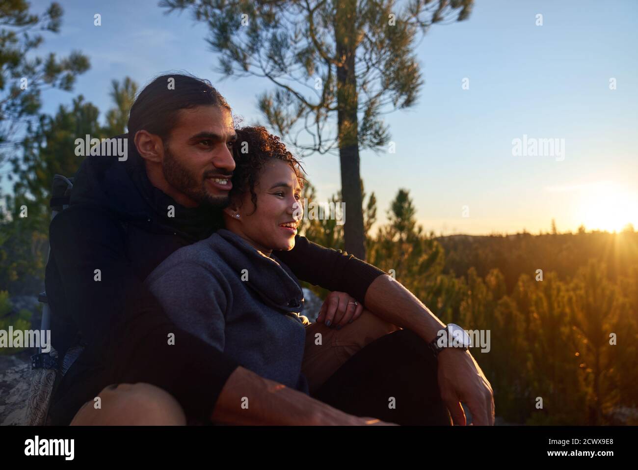 Jeune couple de randonneurs affectueux qui profite du coucher de soleil dans les bois Banque D'Images