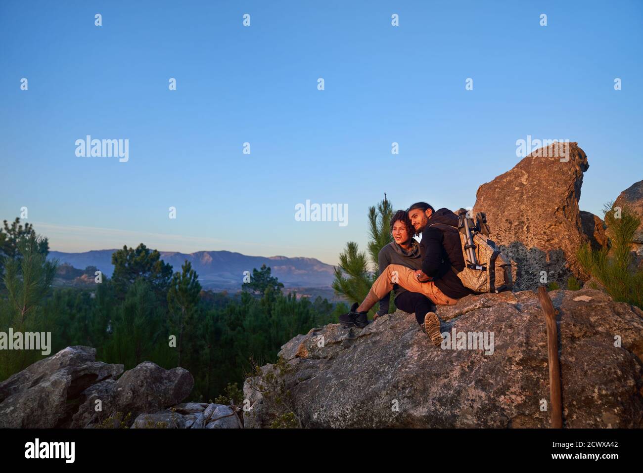 Jeune couple de randonneurs se détendant sur le rocher et appréciant le coucher du soleil Banque D'Images